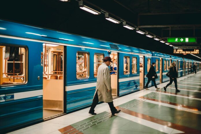 Dynamic scene of passengers moving on a subway platform with a blue train in an urban environment.