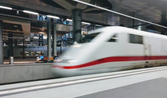 Blurred motion of a high-speed train departing from a modern urban station platform.